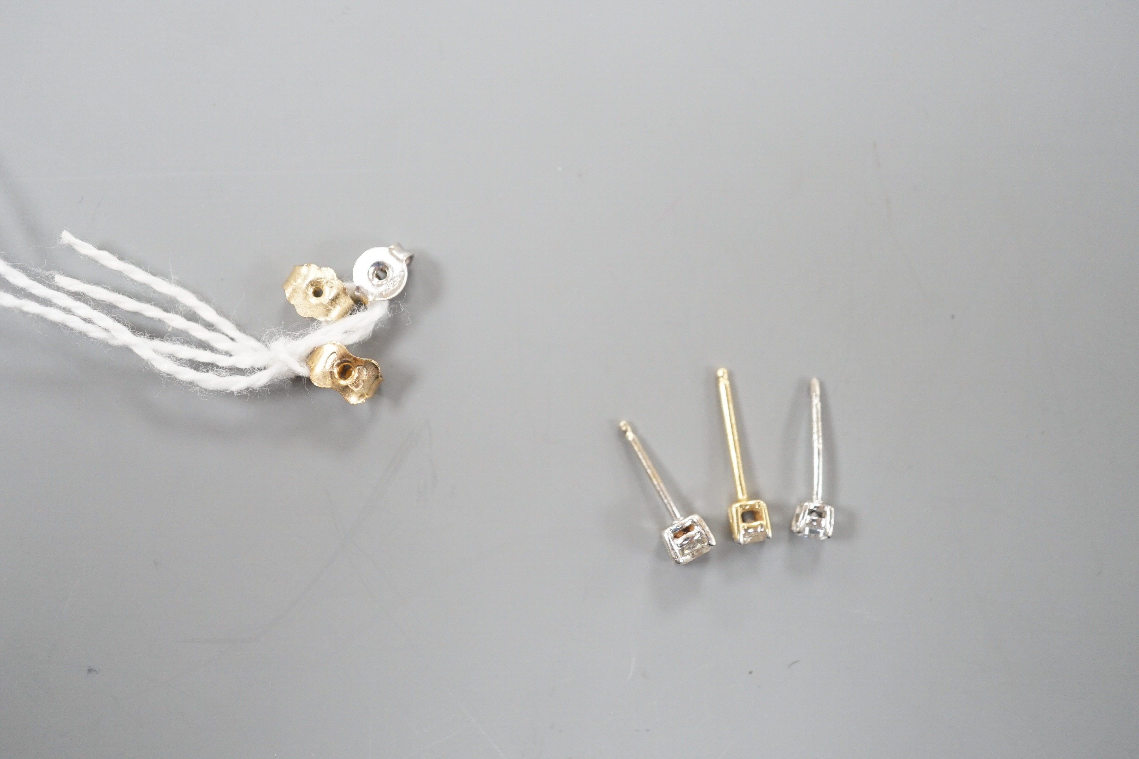 Two odd diamond set ear studs, the stones of various sizes and one paste set ear stud, gross weight 1.3 grams.